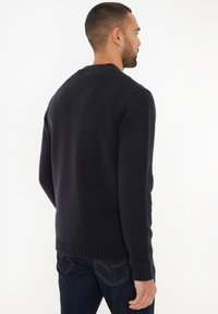 Donker marineblauwe gebreide trui met een ronde hals, geribbelde manchetten en boord, met een textuurafwerking en een normale pasvorm, gedragen met jeans.