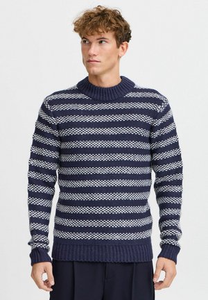 Pull en tricot rayé bleu marine et blanc avec un col et des poignets côtelés, présentant un motif texturé de rayures épaisses et fines alternées.