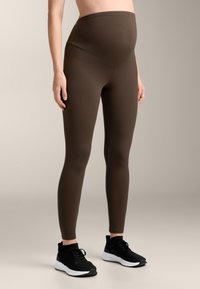 Ruske raska leggings z visoko pasom in gladko teksturo, ujemajoče z črnimi športnimi čevlji z belimi podplati.