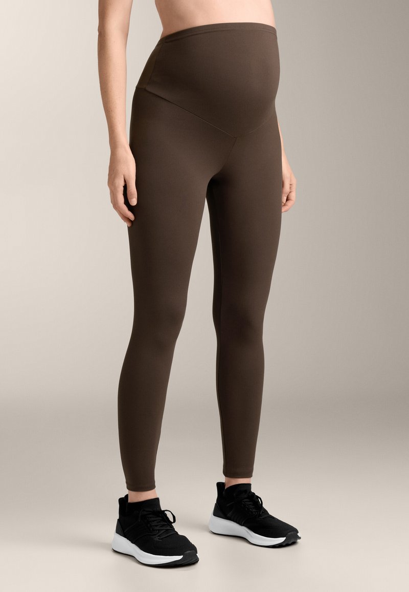 Ruske raska leggings z visoko pasom in gladko teksturo, ujemajoče z črnimi športnimi čevlji z belimi podplati.