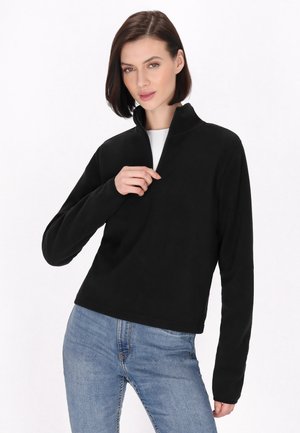Sort fleece pullover med halvlukket krave, lange ærmer og en blød tekstur, parret med lyseblå denim jeans.
