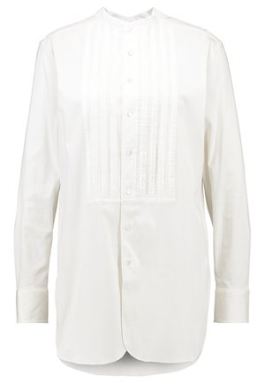Pitkähihainen valkoinen paita, jossa etuosassa laskospaneeli, napitus, pystypystykaulus, slim fit -malli ja yksinkertaiset kalvosimet.