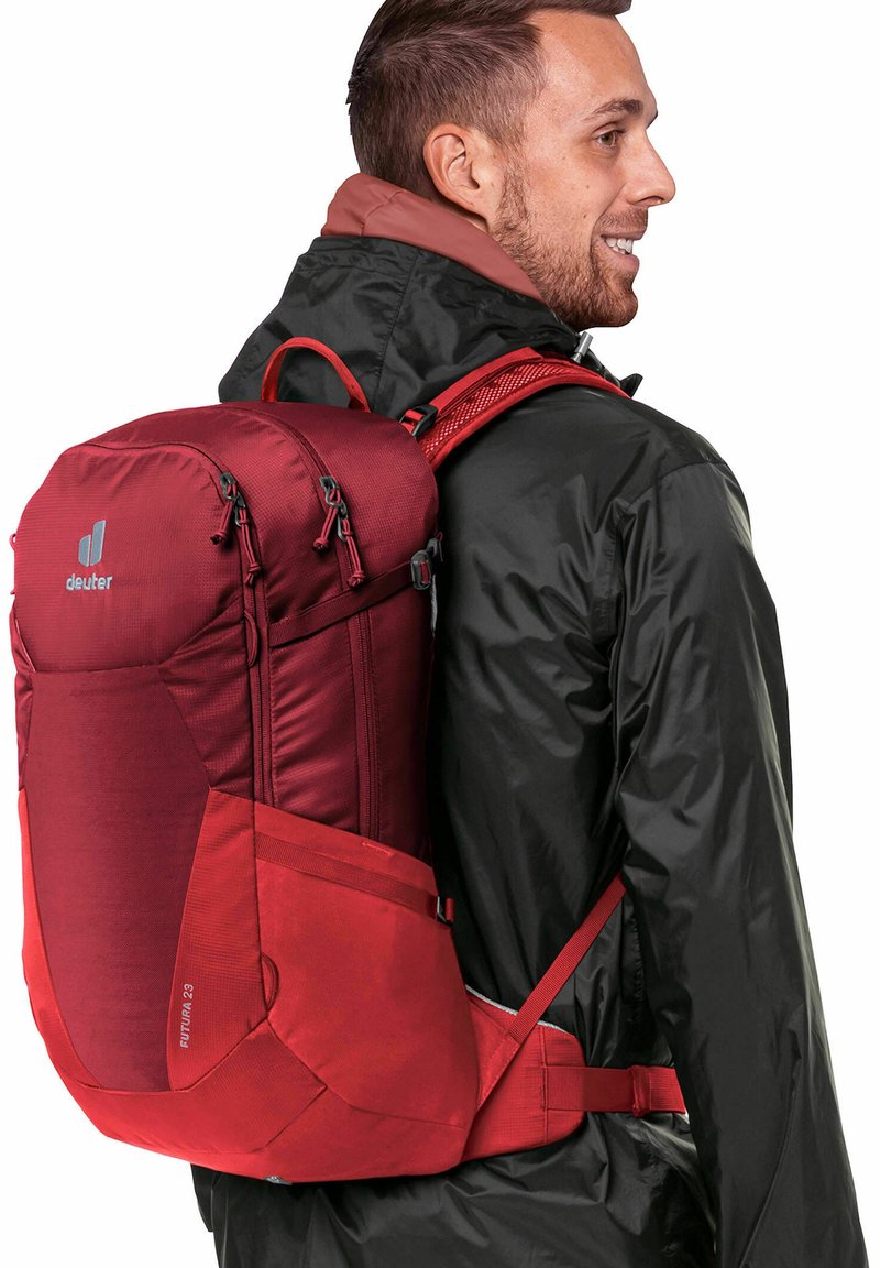 Red hiking backpack with multiple zippered compartments, adjustable straps, and a padded back. Made from durable fabric with textured accents.