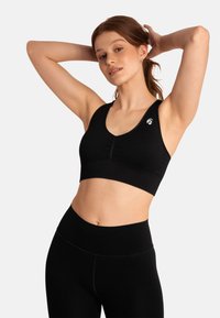 Zwarte sportieve crop top met een geribbelde textuur, diepe V-hals, vouwingdetails aan de voorkant en een klein logo aan de linkerkant. Naadloos ontwerp.