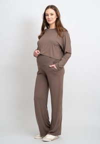 Bruine lange mouw top en bijpassende wijde broek, gemaakt van zachte stof, met een relaxte pasvorm en zijzakken.