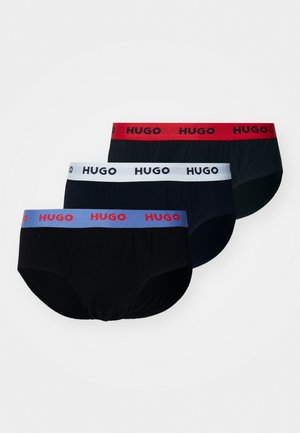 Trzy pary męskich majtek w kolorach czarnym, granatowym i ciemnozielonym. Każda z nich ma kontrastującą gumkę z logo "HUGO" w kolorach czerwonym, białym i jasnoniebieskim.