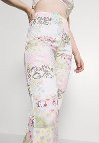 Kleurige, gemusterde broek met een patchworkdesign met Hello Kitty en bloemmotieven. Gemaakt van textiel met een structuur, in pastelkleuren.