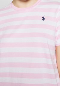 Camiseta de manga corta en rosa claro con rayas blancas, hecha de algodón. Presenta un pequeño logo en navy en el área del pecho izquierdo.