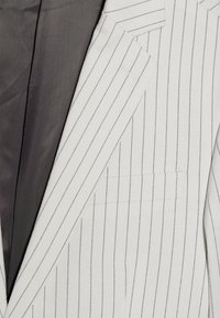 Herrer pinstribet blazer i lysegrå og hvidt stof med en glat tekstur og mørkegrå foring. Har udskårne klapper og en brystlomme.