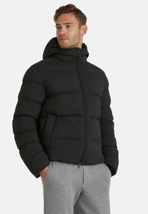 Black puffer jacket with a zip front, hood, and side pockets. Features a quilted design and smooth texture. Styled with gray sweatpants.