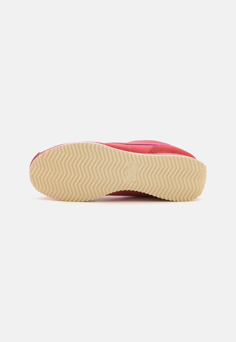 Baskets avec une tige synthétique rose et des détails de couture, complétées par une semelle en caoutchouc beige texturé avec un motif en chevrons.