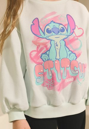 Hellblaues Sweatshirt mit pinkem und blauem Stitch-Graphic, runder Ausschnitt, Puffärmel, gerippte Bündchen und "STITCH OHANA" Text.