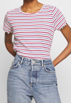 Striped short-sleeve T-shirt in white, red, and blue cotton with a round neckline and frayed edges. Paired with high-waisted denim jeans.