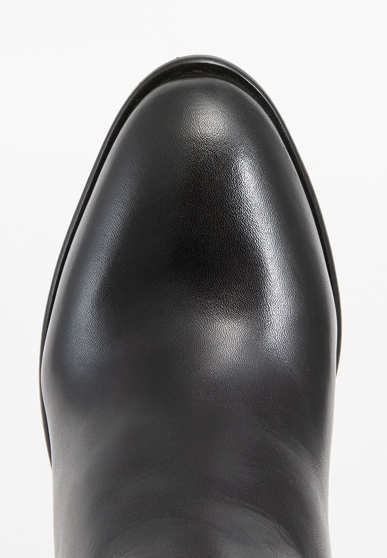 Schwarze Leder-Ankle Boots mit glatter Oberfläche, spitzem Fuß und dezentem Glanz. Verfügt über eine dünne schwarze Sohle und minimalistisches Design.