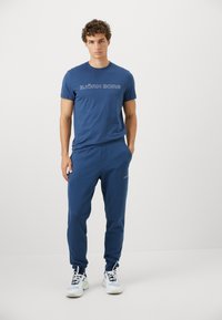 Σετ μπλούζας navy blue και παντελόνι φόρμας με λογότυπο, κατασκευασμένο από μαλακό βαμβακερό ύφασμα. Οι φόρμες διαθέτουν ελαστική μέση και πλαϊνές τσέπες. Ελαφριά σχεδίαση.