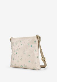 Borsa a spalla in tessuto beige con ricamo floreale in teal e argento. Presenta una tracolla removibile e una forma rettangolare slim.
