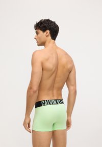 Boxeri scurți de culoare verde mentă, cu un tiv negru pe care scrie "CALVIN KLEIN" în alb. Material neted și design ajustat. Vedere din spate.
