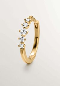 Anillo de oro con cinco piedras preciosas redondas y transparentes engastadas en garras, acabado liso con una banda redondeada. Superficie pulida con reflejos de luz.
