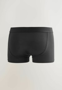Costumi da bagno neri da uomo con vita elastica, tessuto liscio e cuciture piatte visibili sul retro su uno sfondo chiaro e semplice.