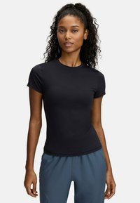 Schwarzes, kurzärmliges Sport-T-Shirt aus dehnbarem Material mit rundem Halsausschnitt und figurbetontem Design, kombiniert mit grauen Sporthosen.