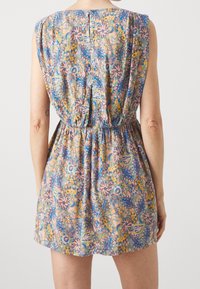 Een mouwloze jurk van lichte stof met een bloemmotief, voorzien van een cinched taille en een achterste knoopsluiting. Kleuren zijn onder andere roze, blauw en geel.