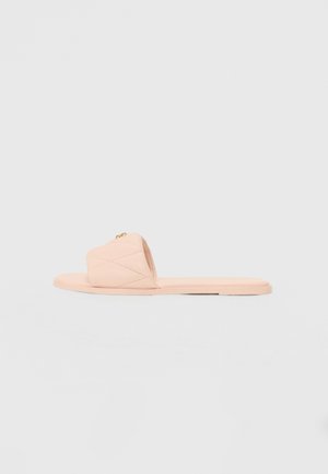 Peach-colored slide sandals with a quilted design, featuring a flat sole and a subtle gold accent on the strap. Soft material with minimal texture.