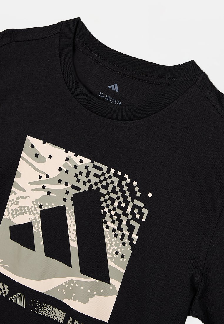 Czarny bawełniany t-shirt z dużą pikselową grafiką w odcieniach beżu i szarości, przedstawiającą geometryczne kształty. Żebrowany okrągły dekolt.