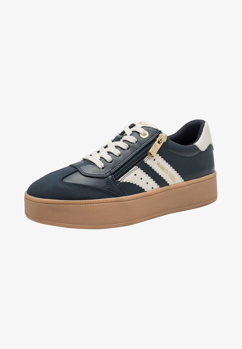 Baskets bleu marine avec semelle beige, lacets blancs, bandes latérales blanches et un détail de fermeture éclair dorée sur le côté.