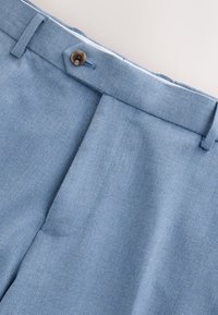 Hellblaue Hose aus strukturiertem Stoff mit einem Knopfverschluss, Gürtelschlaufen und einer maßgeschneiderten Passform.