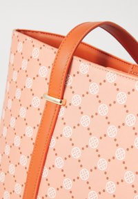 Sac à main orange clair avec une surface à motifs composée de logos circulaires blancs reliés par des lignes pointillées et une poignée orange uni avec un fermoir doré.