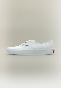 Baskets Vans blanches basses avec lacets, semelle en caoutchouc, et petit logo Vans sur le côté, vues de profil sur un fond neutre.