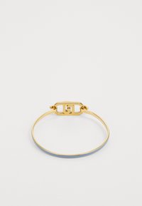 Gouden metalen armband met een gladde afwerking en een sluiting met een uitsnede van het logo-ontwerp. De band heeft een subtiele blauwe accent.