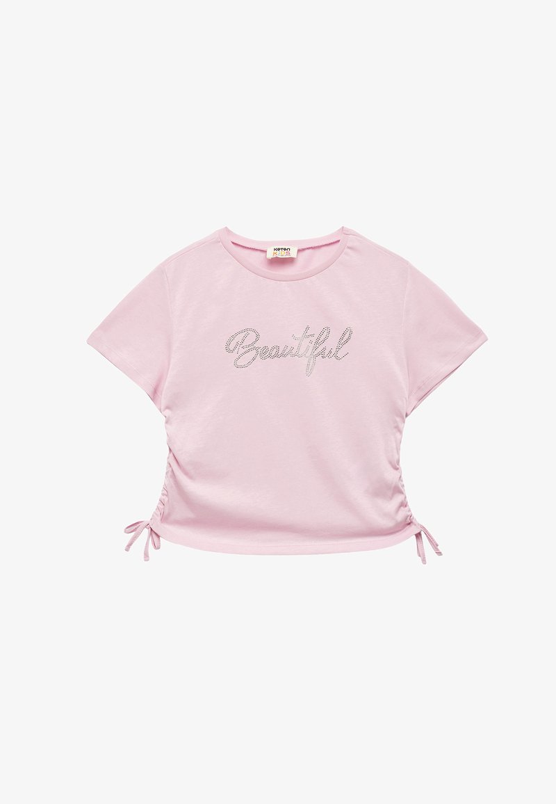 Camiseta de manga corta de color rosa claro, con un diseño fruncido y cordones en los laterales, y el texto metálico "Beautiful" en el frente.