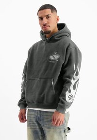 Grijze hoodie van een katoenmix met een voorzak, voorzien van witte vlamgraphics op de mouwen en een logo op de borst. Zachte textuur.