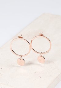 Ohrringe aus roségoldenen Hohldraht mit einer glatten Oberfläche, die mit einem runden Anhänger ergänzt sind, der von dem Ohrhänger hängt.