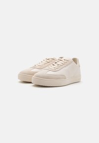 Sneaker beige con un corpo in pelle liscia, punta in suede a contrasto e lacci piatti, dotate di una suola in gomma texturizzata.