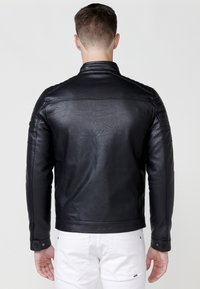 Giubbotto in pelle sintetica nera con una vestibilità slim, spalle strutturate e dettagli trapuntati sulle maniche. Presenta un colletto classico e polsini a scatto.