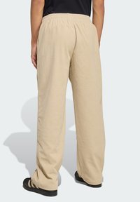 Beige corduroy pants with a relaxed fit, featuring an elastic waistband and vertical ribbed texture. Worn with black slip-on shoes.