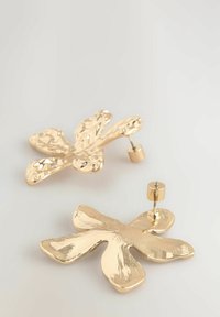 Aranylevél formájú fülbevalók struktúrált felülettel, biztos rögzítést biztosító tűs zárral. Egyszerű design, de merész, fényes kivitel.