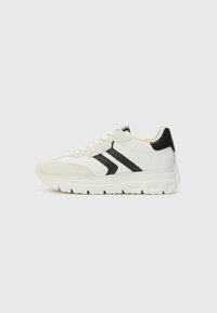 Hvite sneakers med svarte detaljer, laget av en kombinasjon av lær og semsket skinn, med rund tå og en teksturert gummisåle.