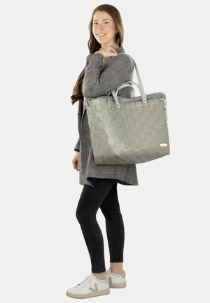 Grau gewebte Tragetasche mit zwei stabilen Griffen, rechteckiger Form und glattem Innenraum. Detaillierte Nähte und natürliche Textur.