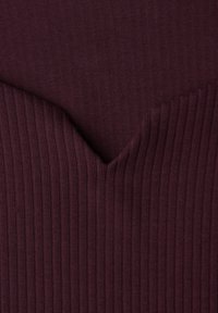 Prążkowany top z dekoltem w serek w ciemnym bordowym kolorze. Charakteryzuje się pionową teksturą prążkowania oraz płynnym przejściem materiału przy linii dekoltu.