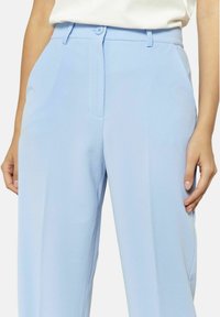 Svetlo modri hlače iz gladkega materiala, s ravnim krojem, stranskimi žepi in gumbom za zapiranje v pasu.