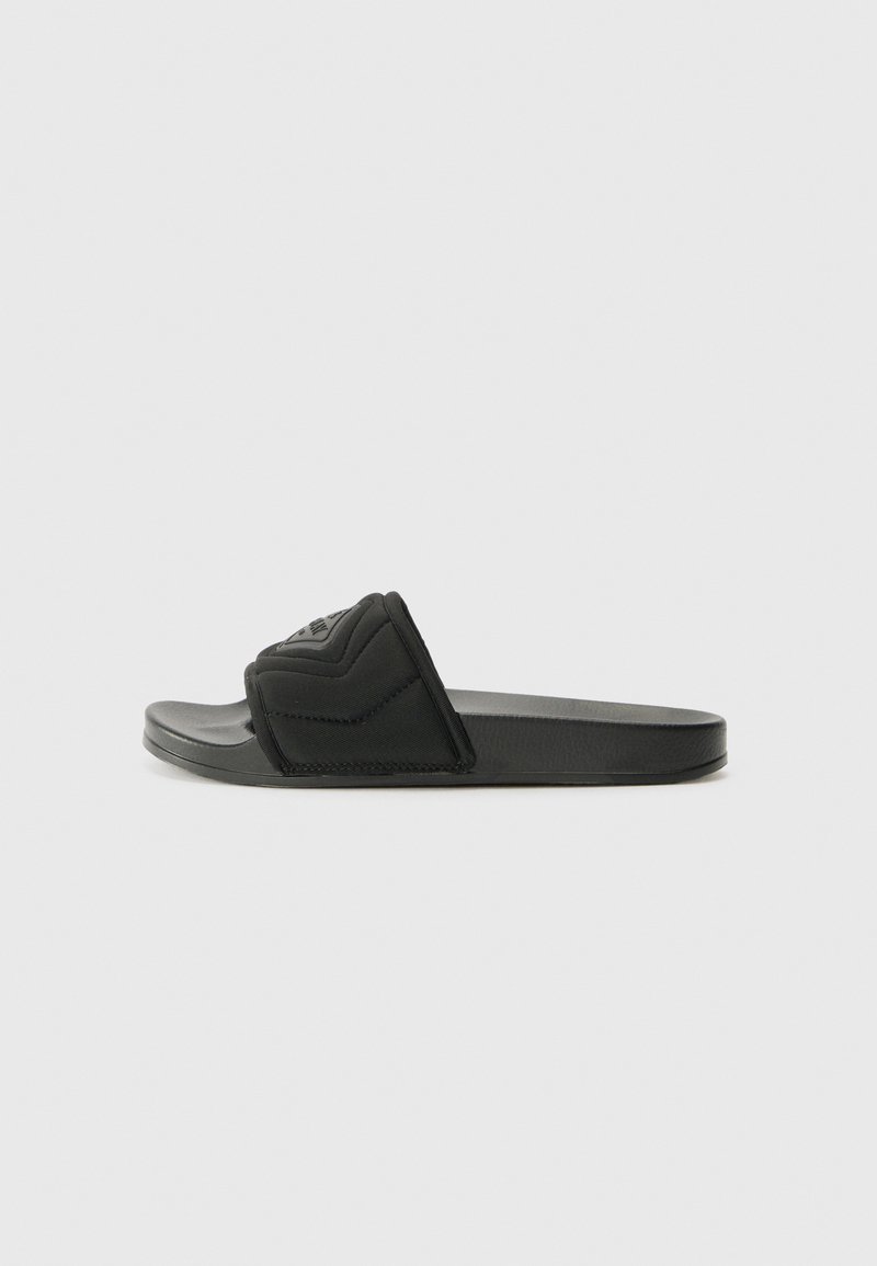 Black slide sandals featuring a textured fabric strap with a raised zigzag pattern, rubber sole, and flat design for easy wear.