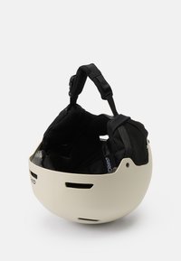 Bijela kaciga s ventilacijskim otvorima, podstavljena crna unutrašnjost, podesive trake i glatka površina. Dizajnirana za sigurnost u ekstremnim sportovima.