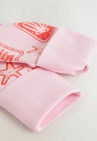 Poignets en tissu rose avec bords roulés et imprimés rouges sur le thème marin, incluant des étoiles de mer et des motifs de coquillages sur un matériau doux.