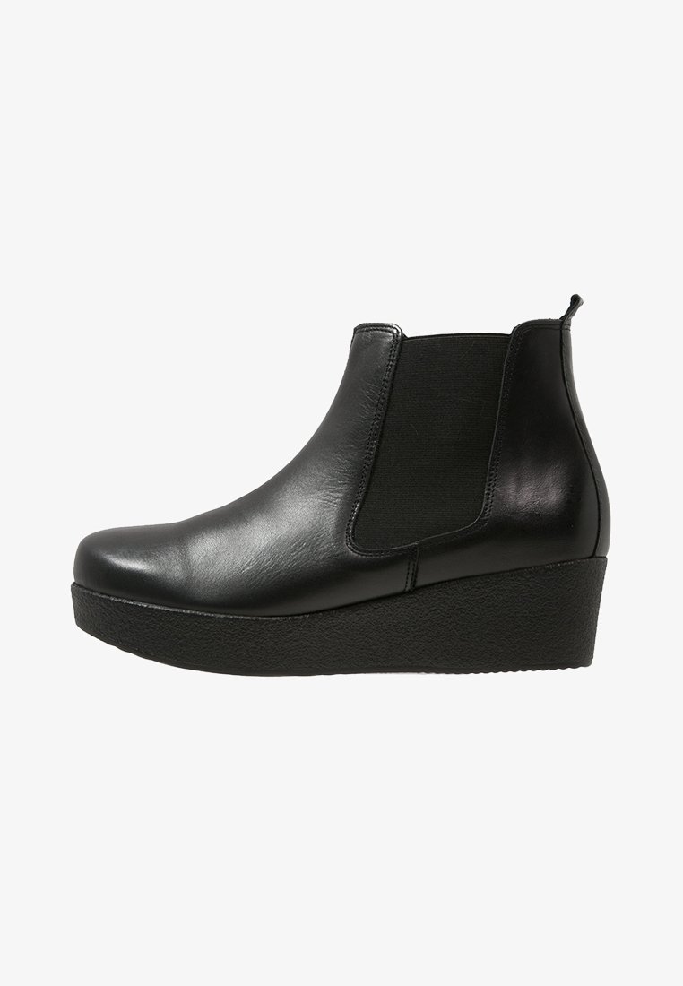 Bottine compensée en cuir noir avec panneaux élastiques sur les côtés et languette à l'arrière, finition lisse et semelle texturée antidérapante.