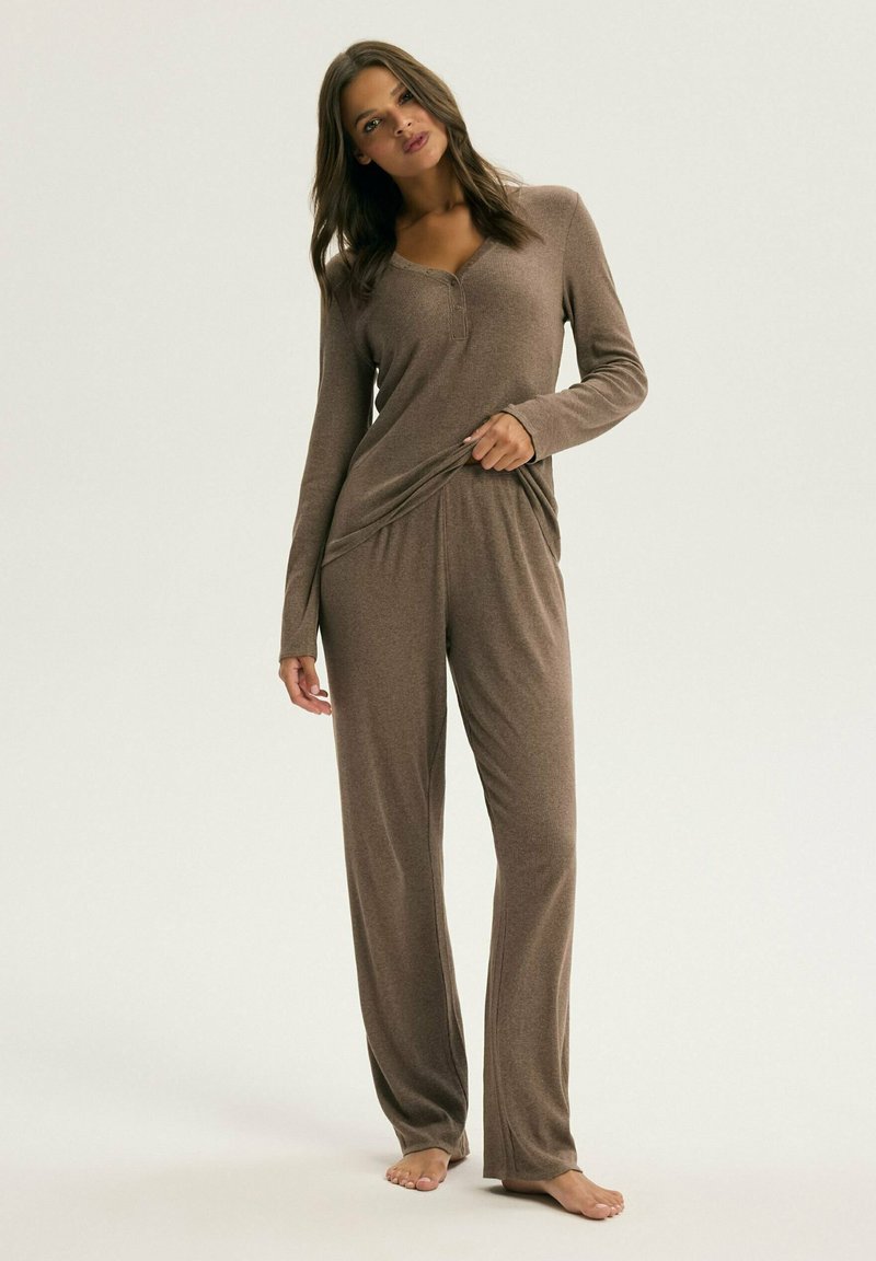 Brązowy zestaw piżamowy z długim rękawem, z dekoltem henley i luźnymi spodniami. Miękka tekstura, gładki materiał i brak widocznych wzorów.