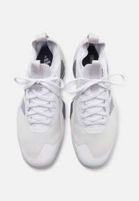 Coppia di sneaker sportive bianche con dettagli grigi e lacci annodati viste dall’alto su uno sfondo semplice.