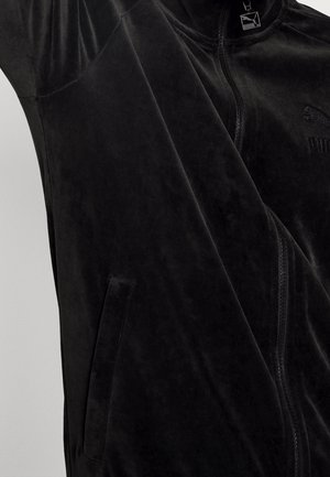 Veste zippée en velours noir avec poche latérale et logo Puma brodé discret sur la poitrine.